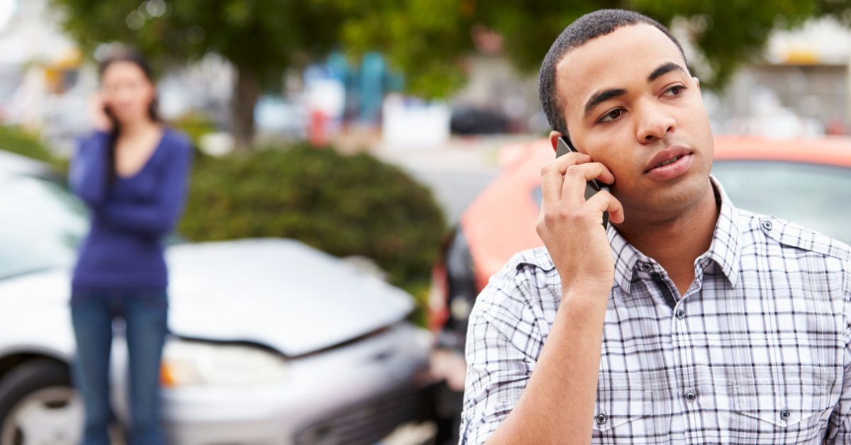 Male Driver Making Phone Call After Traffic Accident With Crash In Background
