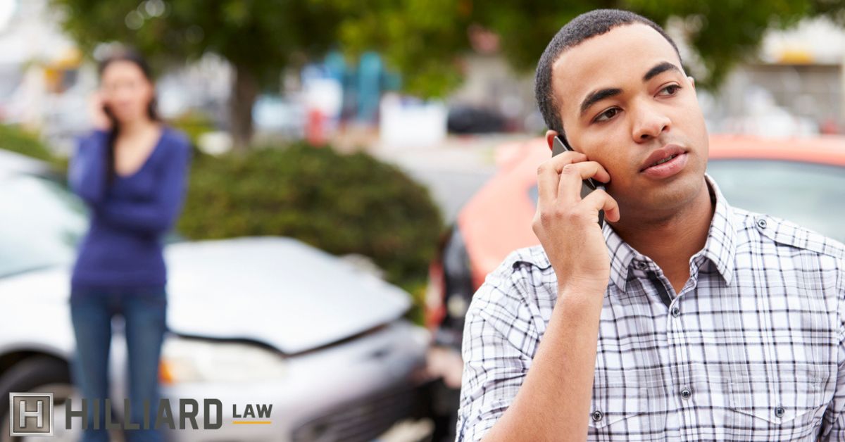 Man on the phone with car accident behind him