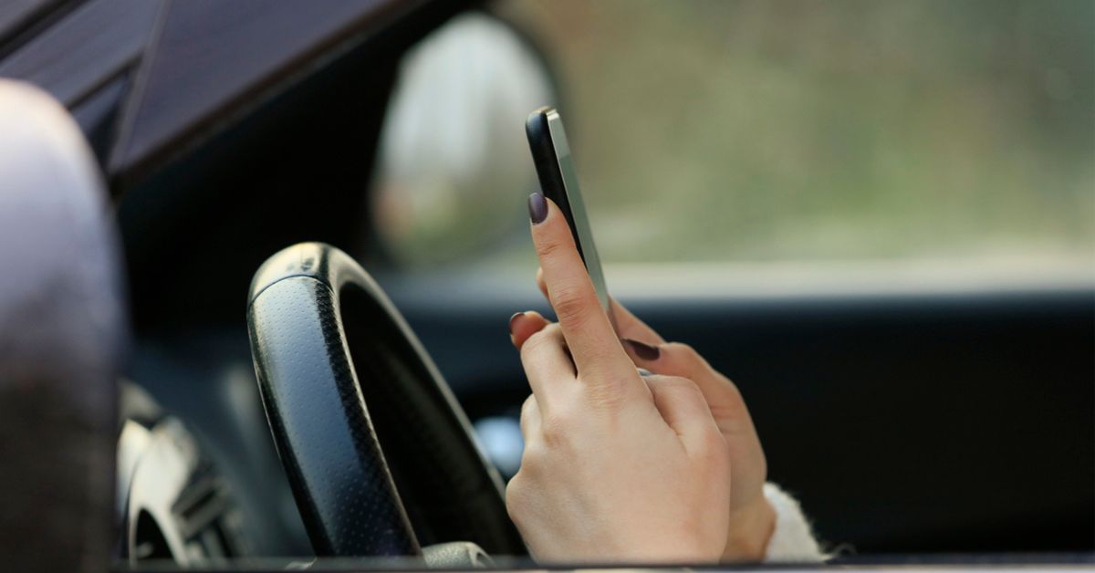 Woman driving car distracted by her mobile phone