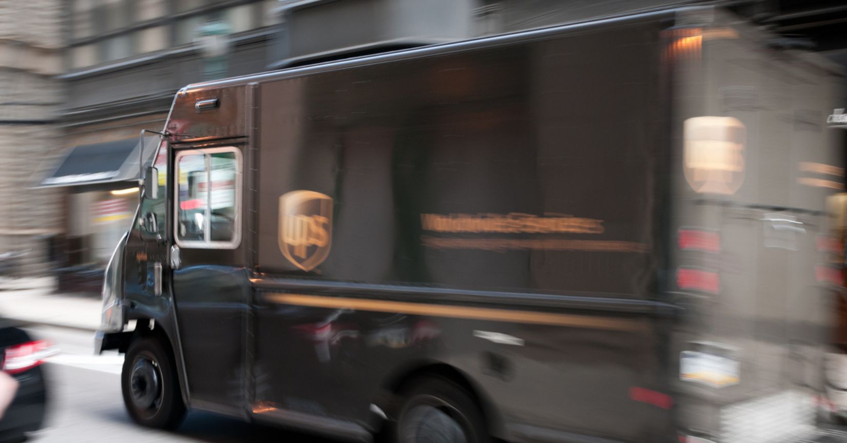 A brown United Parcel Service (UPS) truck driving through downtown