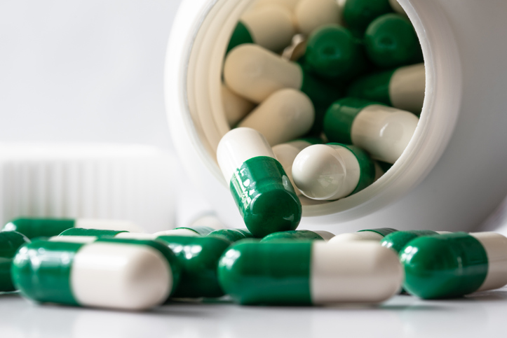 Green and White Capsules Spilled from a Bottle