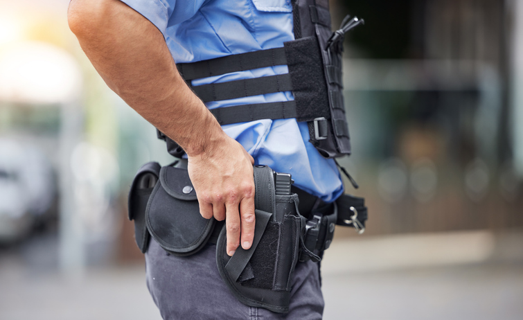 Gun, uniform and police in the city for crime, security and outdoor justice in the street. Law, safety and a closeup of a man with a weapon in town for legal services, criminal or protection stock photo