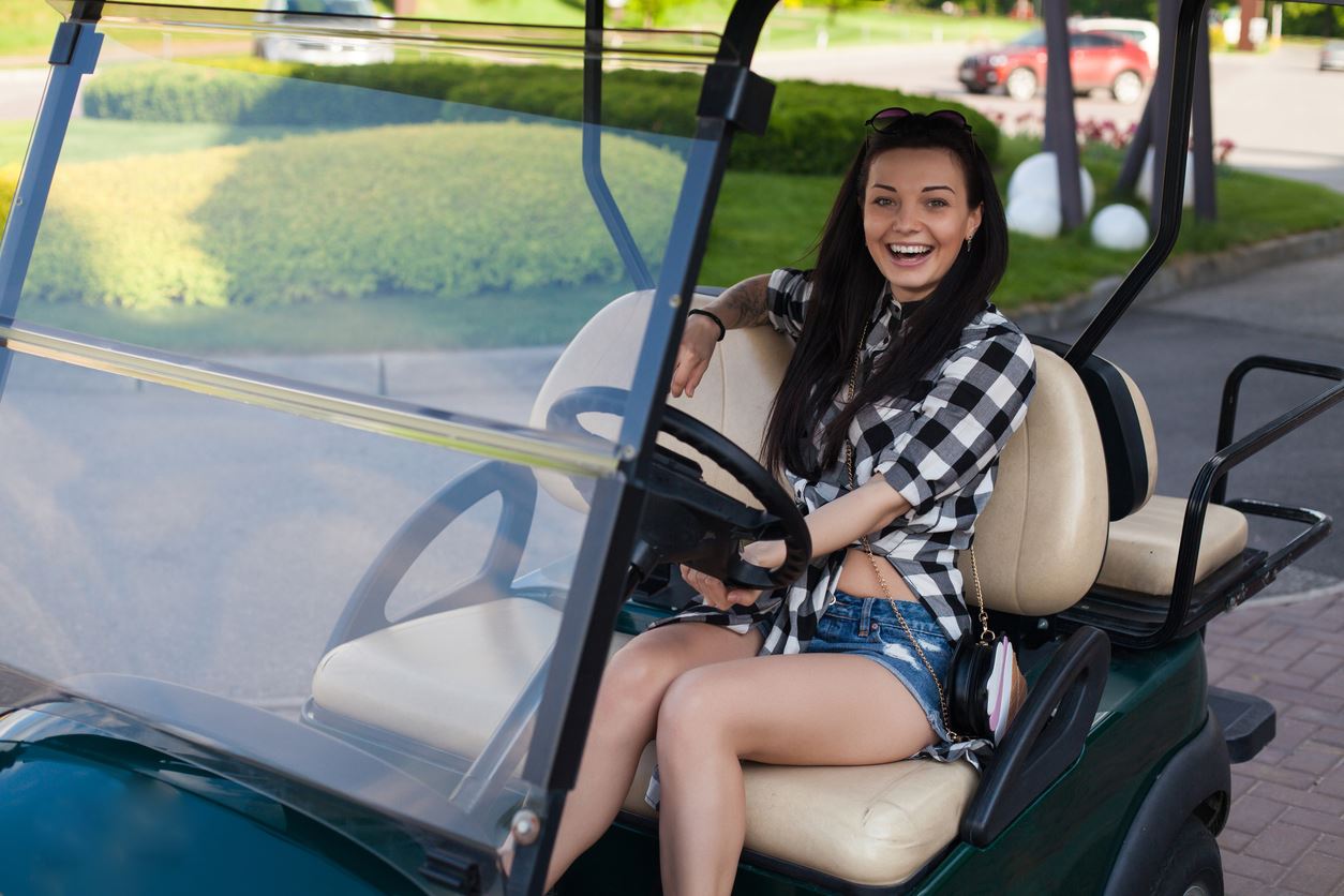 Teen driving gold cart in neighborhood