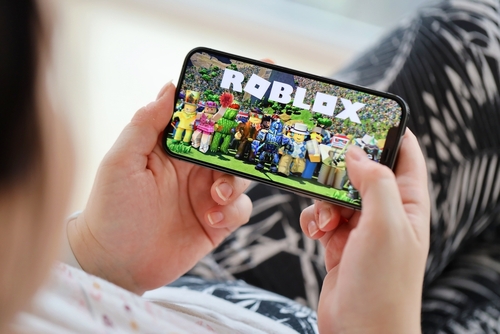 Roblox mobile iOS game on iPhone 15 smartphone screen in female hands during mobile gameplay. Mobile gaming and entertainment on portable device