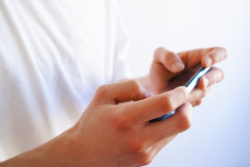 Young man playing a game with his smart phone ( mobile phone) held horizontally