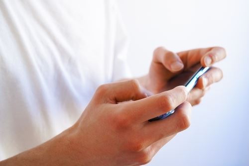 Young man playing a game with his smart phone ( mobile phone) held horizontally