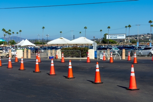Del Mar Fairgrounds parking lot set up with orange cones, tents, and barriers for pedestrian safety and rideshare coordination under a clear blue sky - Del Mar, California, USA - August 25, 2024