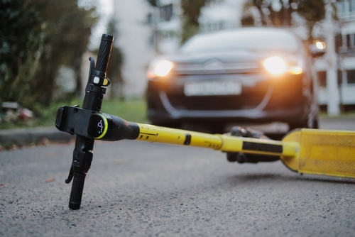 Yellow electric scooter lies on the ground after crash. Accident with car and electric scooter.