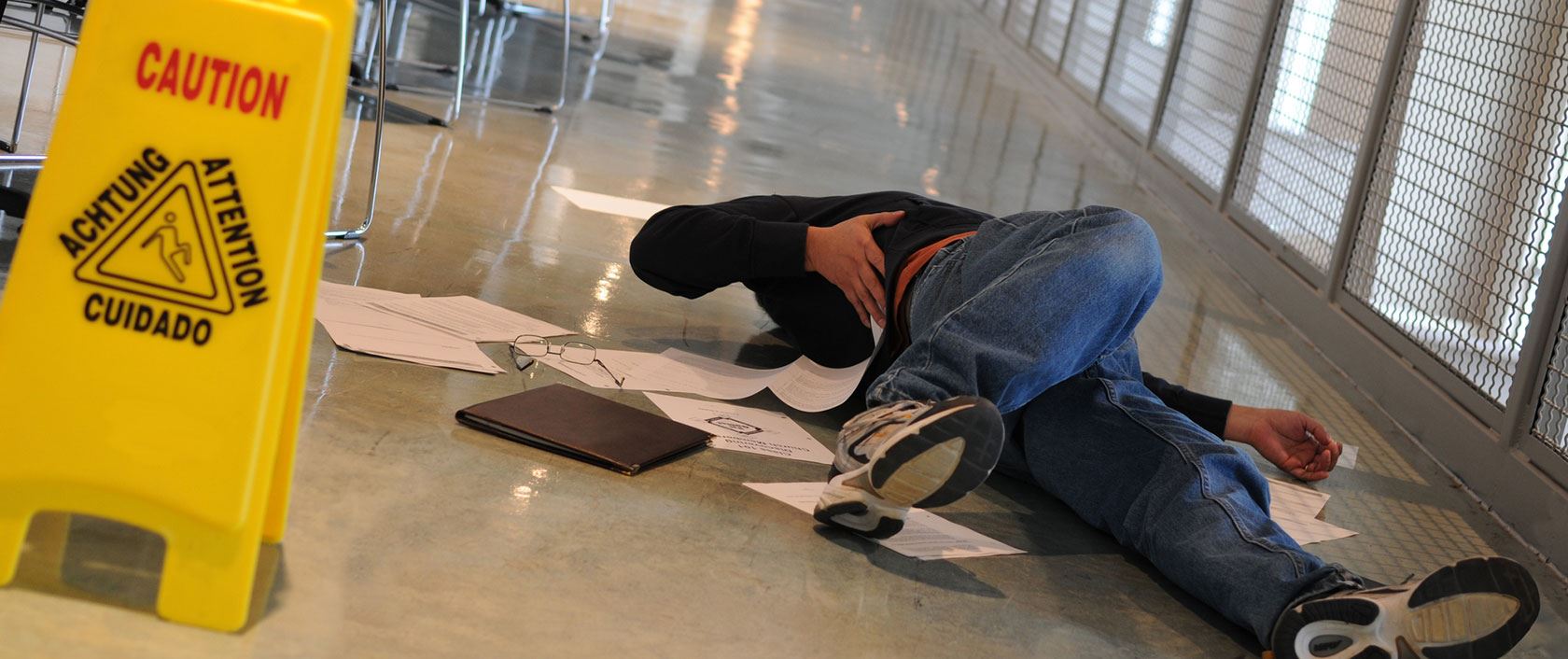 image of an empty space, in the foreground is a yellow caution sign alluding to a wet floor, warning against a slip and fall